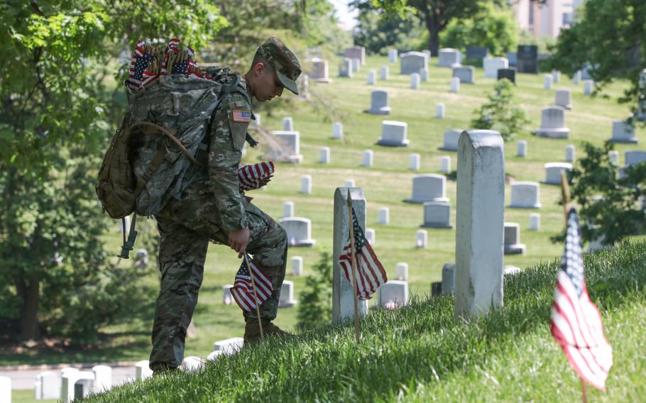 A soldier with the U.S. Army's 3rd Infantry Regiment places a flag at a grave at Arlington National Cemetery as The Old Guard visited graves throughout the cemetery for Flags In on May 24, 2018. 