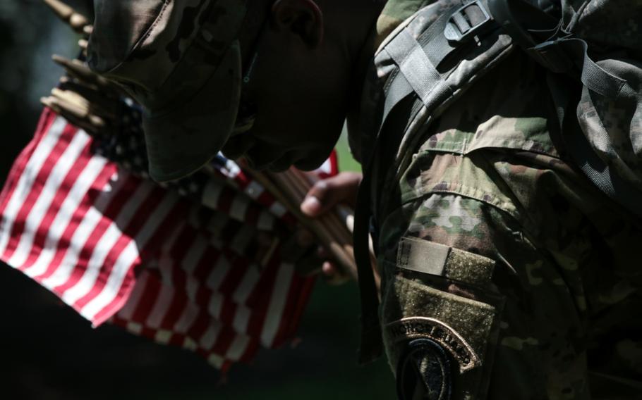 A soldier with the U.S. Army's 3rd Infantry Regiment, better known as The Old Guard, places a flag at a grave at Arlington National Cemetery as The Old Guard visited graves throughout the cemetery for Flags In on May 24, 2018. 