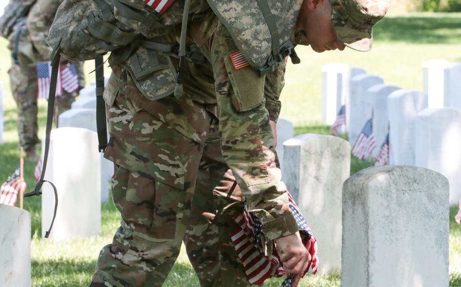 A soldier with the U.S. Army's 3rd Infantry Regiment, better known as The Old Guard, places a flag at a gravesite at Arlington National Cemetery as The Old Guard visited graves throughout the cemetery for Flags In on May 24, 2018. 