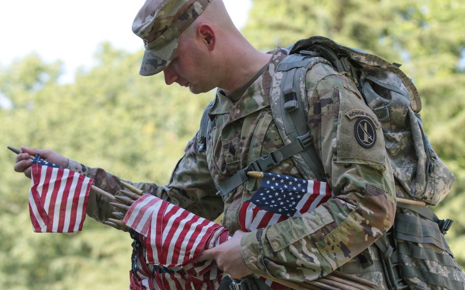 Spc. Richard Broseman, 32, selects a flag to place at a gravesite at Arlington National Cemetery at Flags In on May 24, 2018. 