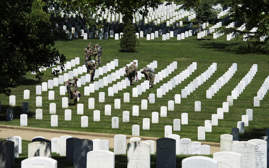 Members of the Army 3d U.S. Infantry Regiment, The Old Guard, place flags at the headstones of fallen military members during its annual Flags In ceremony at Arlington National Cemetery on May 24, 2018, in Arlington, Va.