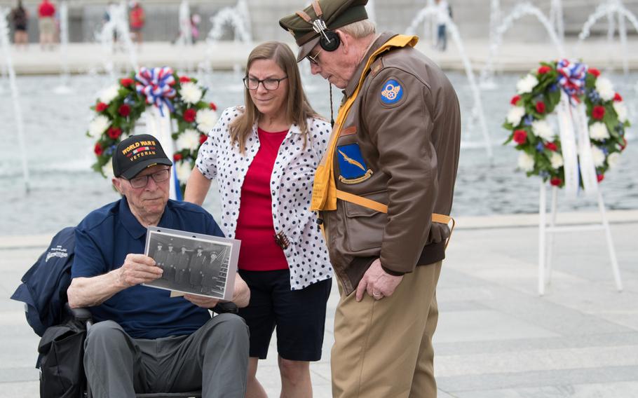 Air Force veteran Charles Drew looks at photographs with his daughter and a volunteer from the National World War II Memorial at a ceremony on June 20. Drew was a radio operator and combat photographer with the 305th Bomb Squad of the Eighth Air Force, where he flew information missions photographing bombed out bridges and roads. 