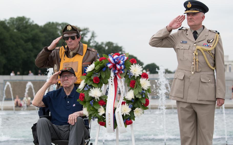 Air Force veteran Charles Drew salutes after placing a wreath at the National World War II Memorial with a representative from the British Embassy and a volunteer from the memorial. 
