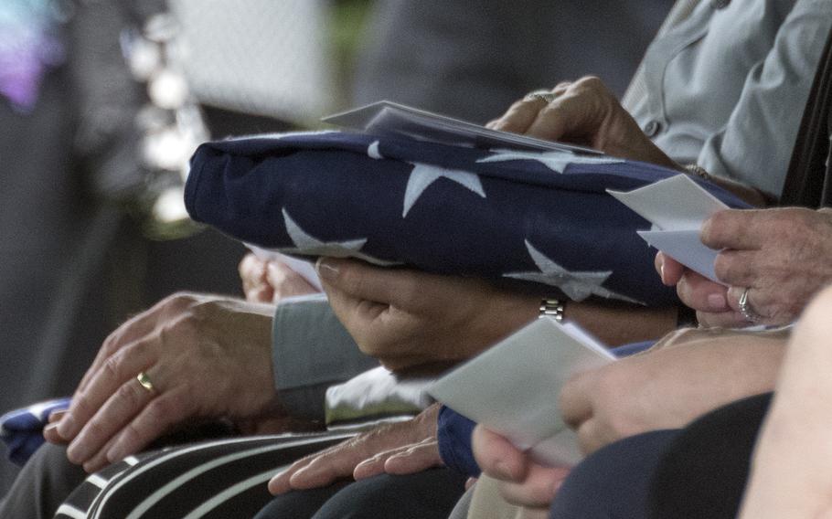 A family holds a flag given to them by the Old Guard during the funeral of five airmen killed in WWII. 