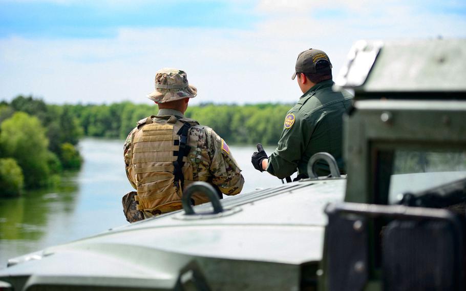 A Texas Guardsmen and a Customs and Border Patrol agent discuss the lay of the land on the shores of the Rio Grande River in Starr County, Texas in April as part of the federal call-up to the Texas Mexico border.