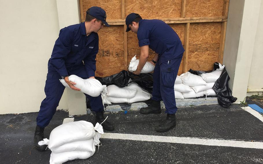 Coast Guard Station Yankeetown crew member Seaman Nicholas Feder hands a sand bag to Fireman Richard Tzoumas-White at the station in preparation for Hurricane Michael, Monday, Oct. 8, 2018. 