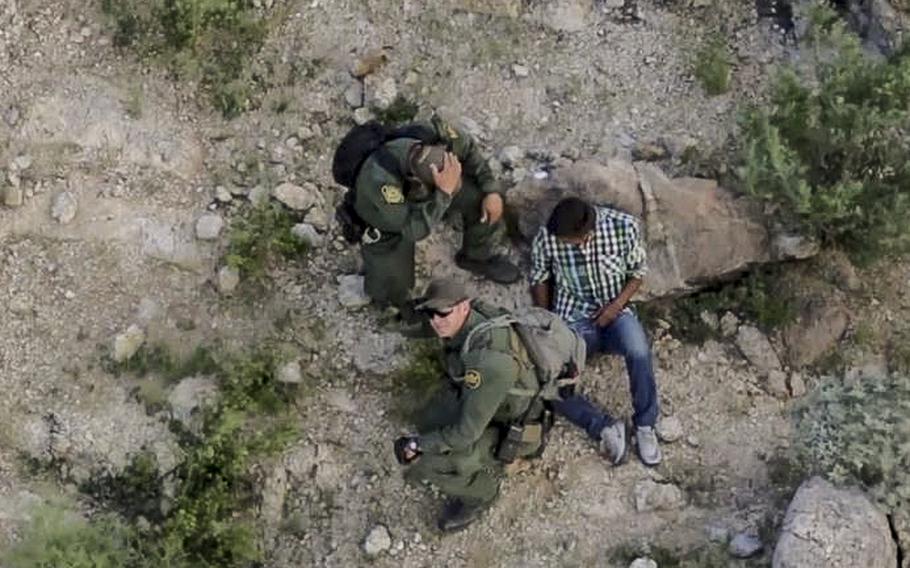 A video screen grab shows U.S. Customs and Border Protection personnel receiving aid from a National Guard helicopter above as they apprehend a suspect.