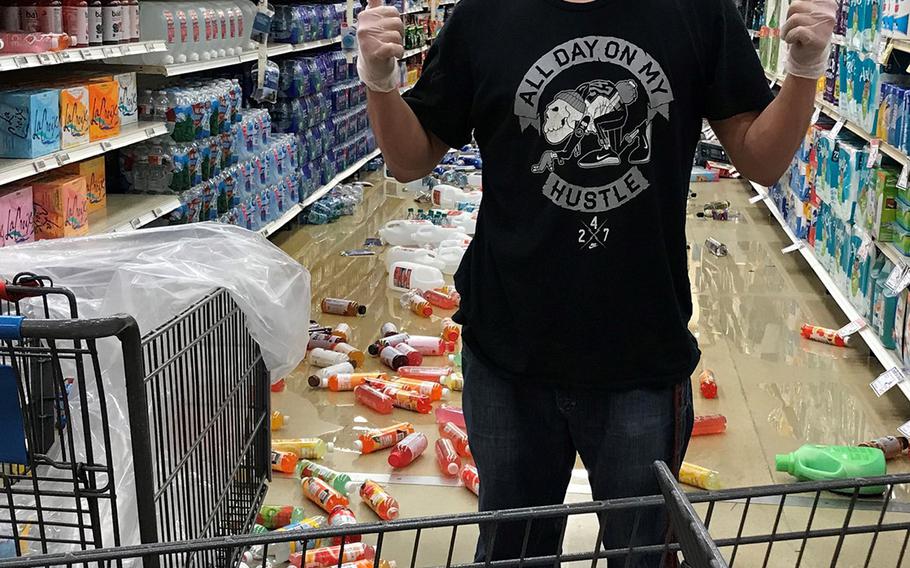 A member of a clean-up crew gives the thumbs-up signal while clutter lines the floor at the base exchange at Joint Base Elmendorf-Richardson, following a massive earthquake which struck the region on Friday, Nov. 30, 2018.