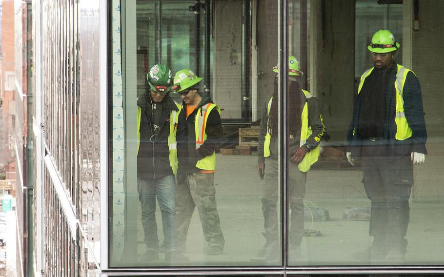 Construction workers watch from an adjacent building as Washington's oldest synagogue building is moved down 3rd St. Northwest to its permanent location at the Lillian and Albert Small Jewish Museum site on January 9, 2019.