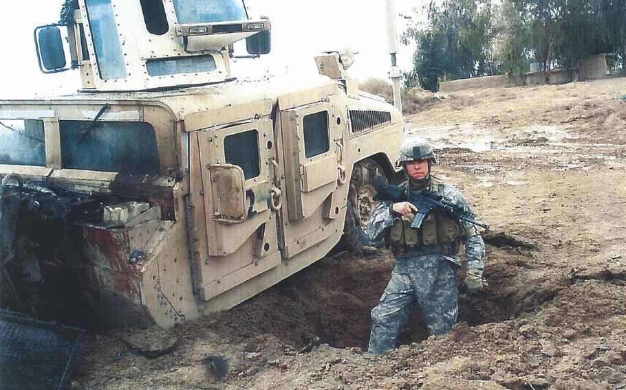 Staff Sgt. Travis Atkins stands in the crater from an improvised-bomb attack that he survived in Iraq. 