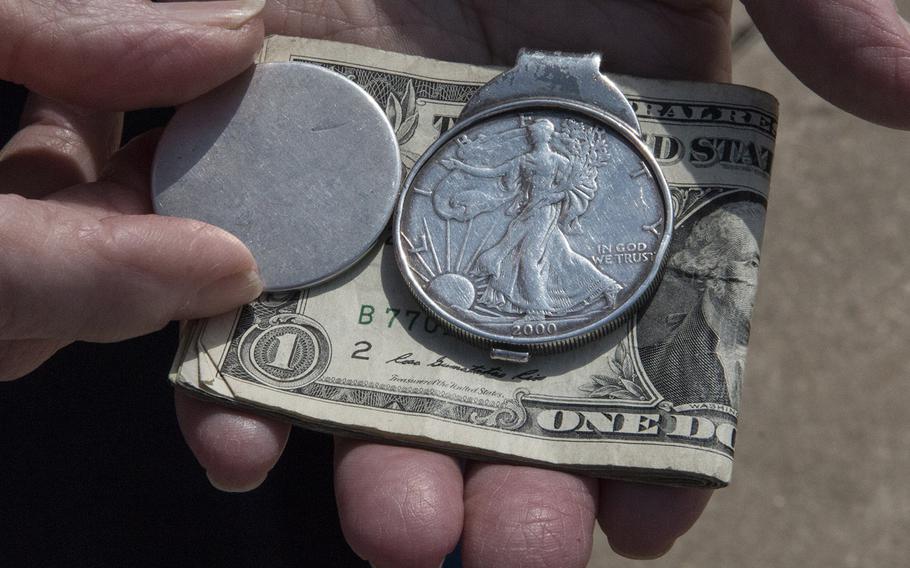 Tom Allen displays his worn-down silver dollar good luck charm, next to an intact coin, as the Greater St. Louis Honor Flight visits the National World War II Memorial in Washington, D.C., March 30, 2019.
