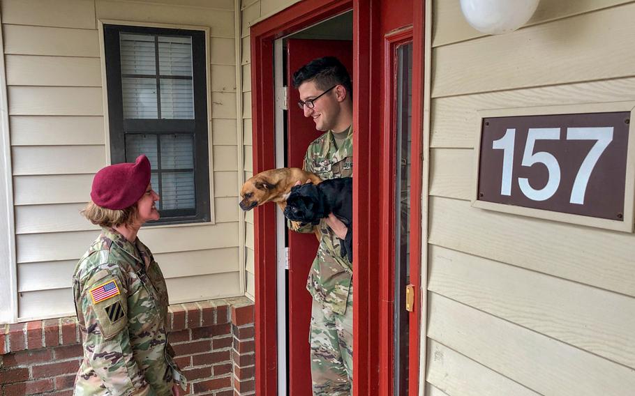 Sgt. Andrew McNeil (right), a public affairs mass communication noncommissioned officer, greets Maj. Tabitha Hernandez, commander, 22nd Mobile Public Affairs Detachment, Headquarters and Headquarters Battalion, XVIII Airborne Corps, at his door with his dogs prior to a command visit at Fort Bragg, N.C., April 5, 2019. L