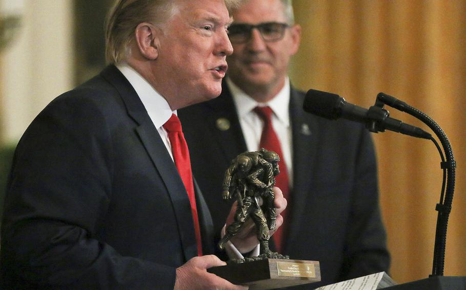 President Donald Trump holds a statue presented to him by Retired Lt. Gen. Michael Linnington, CEO of the Wounded Warrior Project at a White House event held Thursday, April 18, 2019.