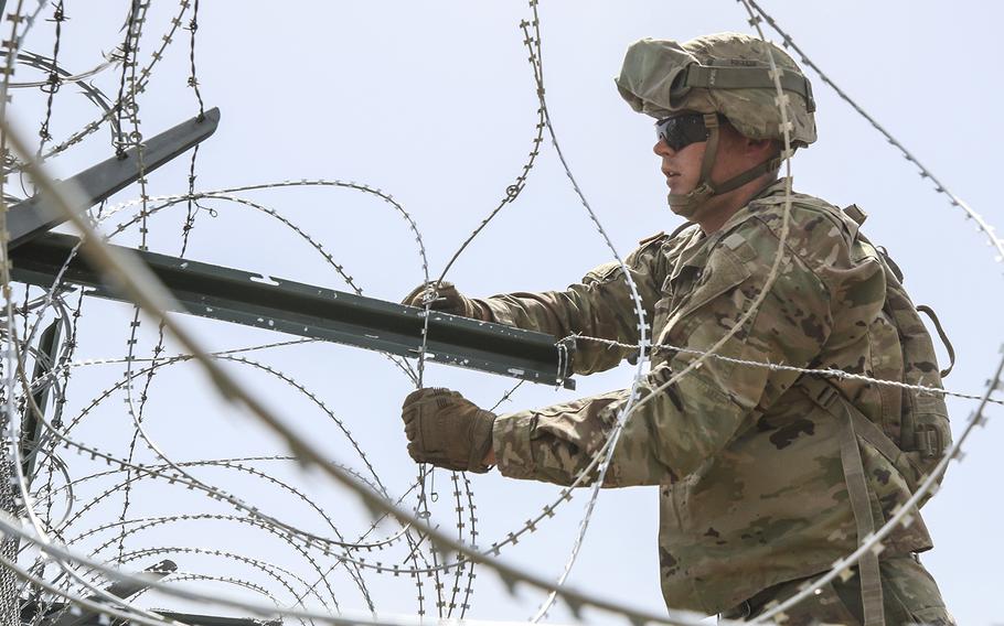 A soldier from the 161st Engineer Support Company (Airborne) secures concertina wire to the existing border fence near the World Trade International Bridge in Laredo, Texas.