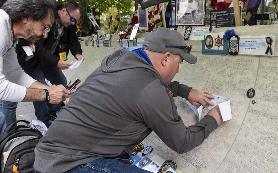 Visitors to the National Law Enforcement Officers Memorial in Washington, D.C. on May 14, 2019, during National Police Week, make pencil rubbings of names on the marble memorial to the fallen.