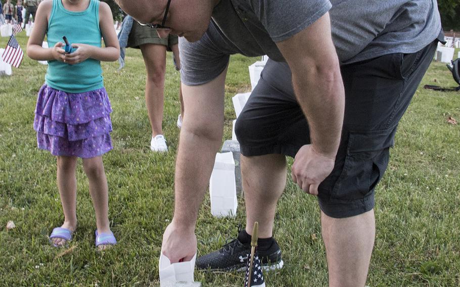 Chief Petty Officer Matthew Rabun lights a candle during the 24th annual luminaria at Fredericksburg National Cemetery in Fredericksburg, Va., May 25, 2019.