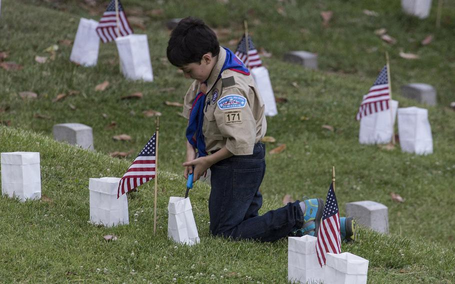 A Boy Scout lights a candle during the 24th annual luminaria at Fredericksburg National Cemetery in Fredericksburg, Va., May 25, 2019.