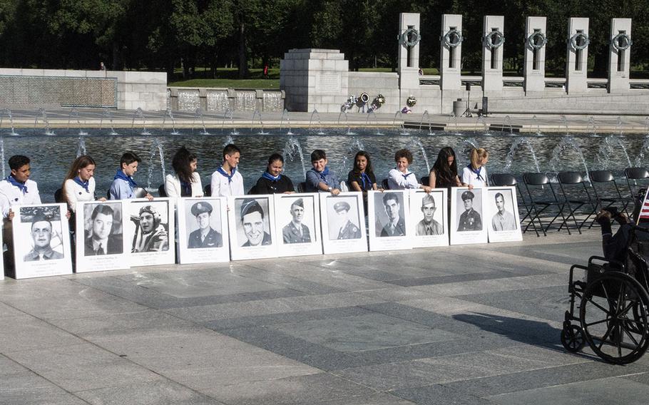 A veteran takes a photo of children holding placards with photos of the fallen on Memorial Day at the National World War II Memorial in Washington, D.C., May 27, 2019.