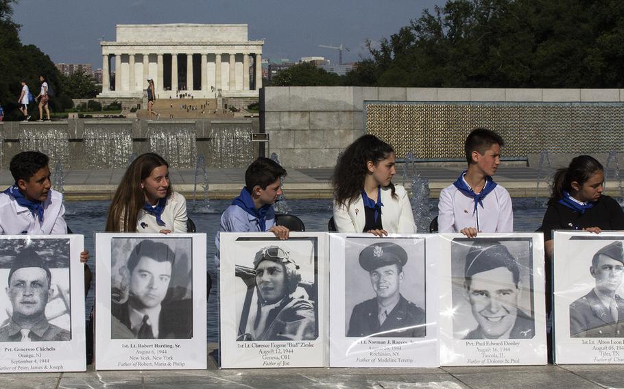 Children hold placards with photos of the fallen on Memorial Day at the National World War II Memorial in Washington, D.C., May 27, 2019.