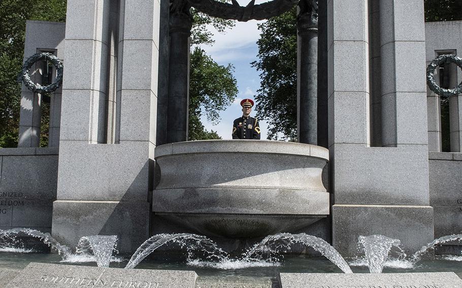 A bugler stands above tributes left at the National World War II Memorial in Washington, D.C., before a ceremony marking the 75th anniversary of D-Day, June 6, 2019.