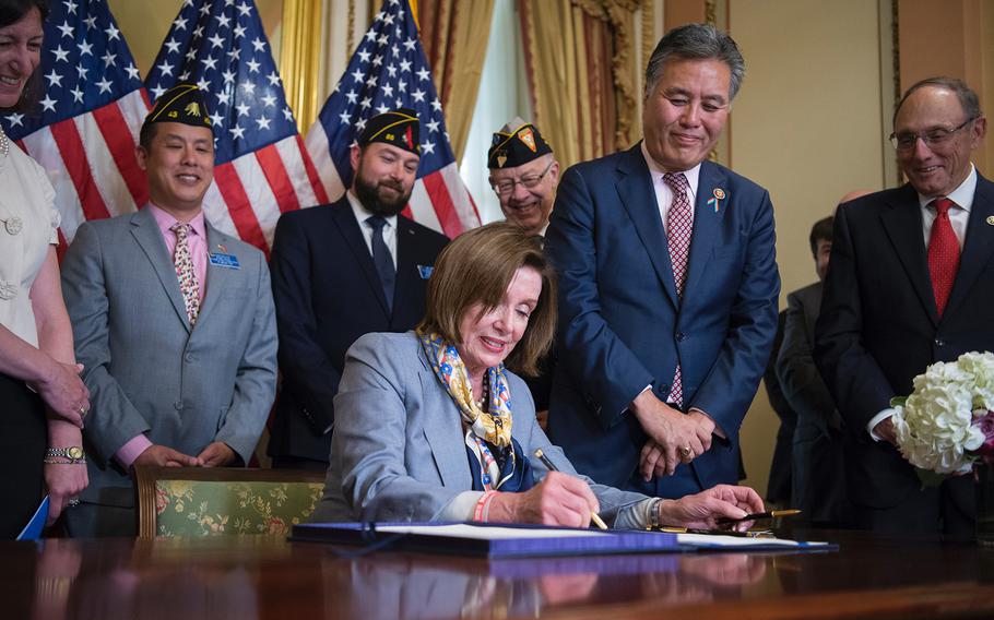 House Speaker Nancy Pelosi, D-Calif., signs the Blue Water Navy Vietnam Veterans Act of 2019, during a ceremony on Capitol Hill in Washington on Tuesday, June 18, 2019. At right looking on are Rep. Mark Takano, D-Calif., the chairman of the House Committee on Veterans' Affairs, and the committee's Ranking Member Rep. Phil Roe, R-Tenn.