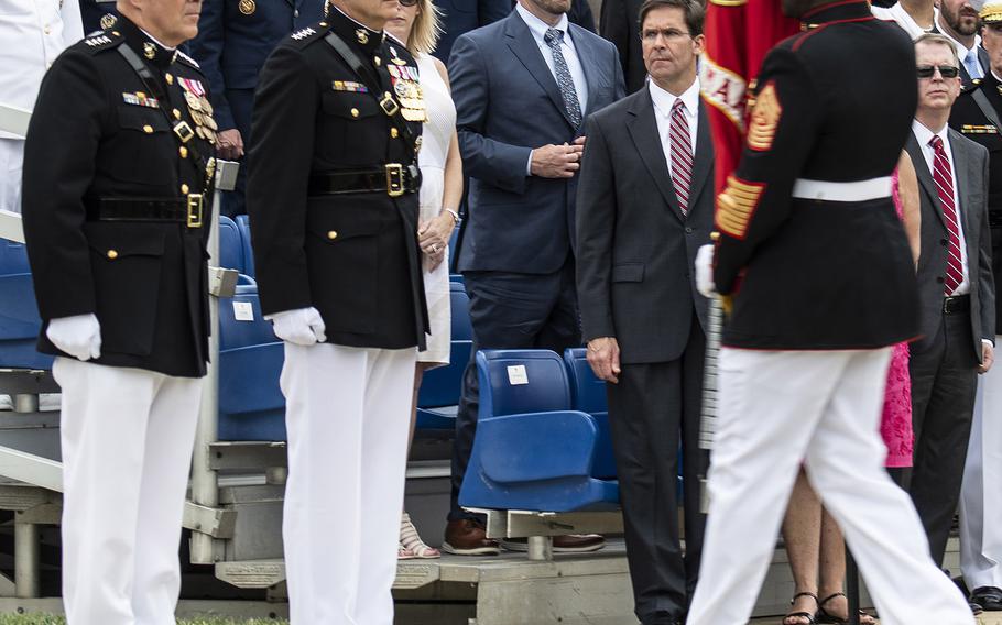 Sergeant Major of the Marine Corps Ronald L. Green carries the Marine colors to retiring Commandant Gen. Robert Neller, left, during a passage of command ceremony at Marine Barracks Washington, D.C., July 11, 2019. Gen. David Berger, second from left, became the 38th Commandant of the Corps. In the background is Acting Defense Secretary Mark Esper.