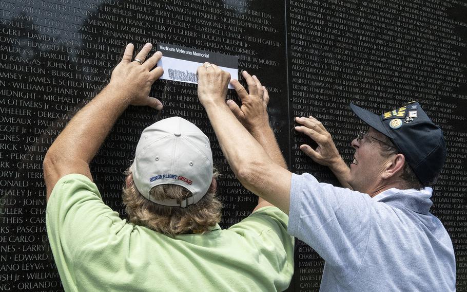 A Vietnam veteran, right, and his Honor Flight Chicago guardian, left, make a rubbing of a name on the Vietnam Veterans Memorial in Washington, D.C. on Wednesday, July 10, 2019. 