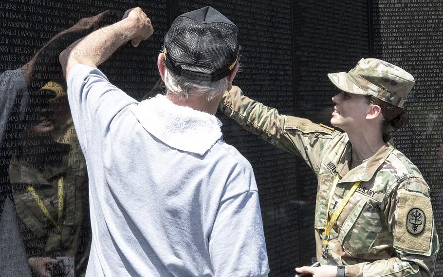 While visiting the Vietnam Veterans Memorial in Washington, D.C. on Wednesday, July 10, 2019, a veteran, left, and his guardian, right, point to a name on the wall. 