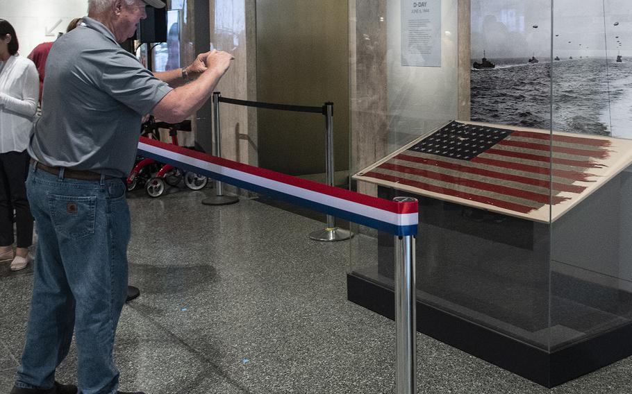 A veteran from the Old Glory Honor Flight takes a photo of a flag that flew on a landing craft control vessel during the storming of Utah Beach, France on D-Day. The artifact was unveiled at the Smithsonian National Museum of American History in Washington, D.C. on July 26, 2019.