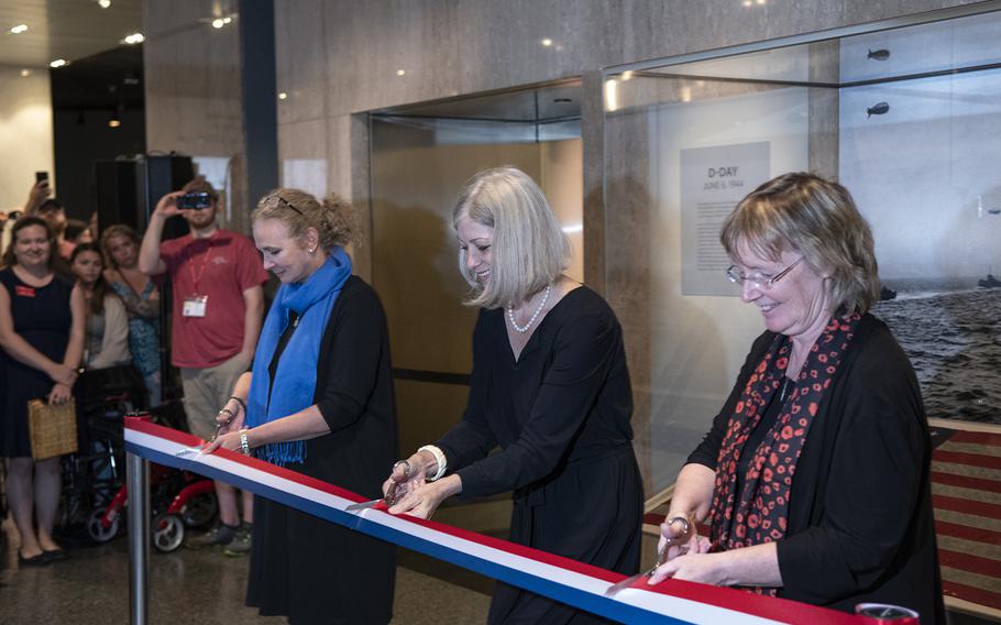 Smithsonian National Museum of American History curator Jennifer Jones, director Anthea Hertig and lead curator of political history Claire Jerry (left to right) cut the ribbon to officially unveil the display of a 48-star flag that was flown on a landing craft control vessel that landed at Utah Beach, France on D-Day. 