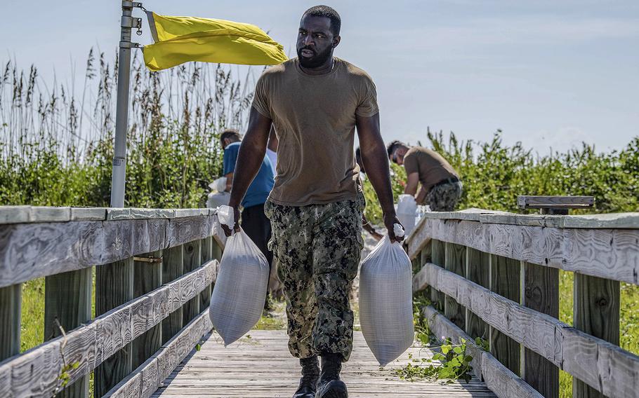 Petty Officer 1st Class Carl Miller, from Brooklyn, N.Y., carries sand bags on Naval Station Mayport in preparation for Hurricane Dorian, Aug. 29, 2019.