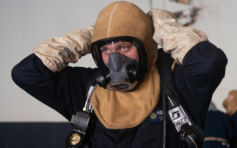 Damage Controlman 2nd Class Cody Cowsert, from Kannapolis, N.C., dons firefighting gear during a general quarters drill aboard the aircraft carrier USS Dwight D. Eisenhower in the Atlantic Ocean during Hurricane Dorian.