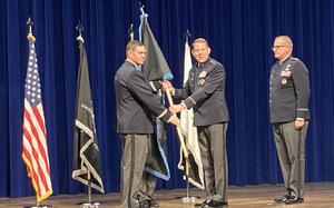 Men in uniform hold a flag during a ceremony.
