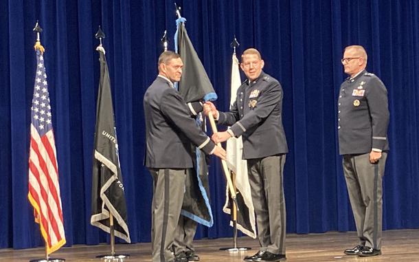 Men in uniform hold a flag during a ceremony.