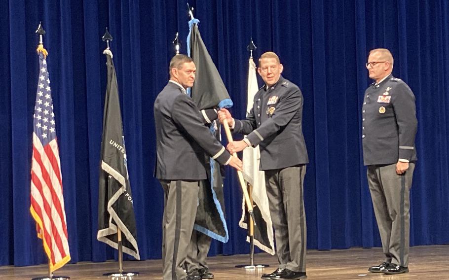 Men in uniform hold a flag during a ceremony.