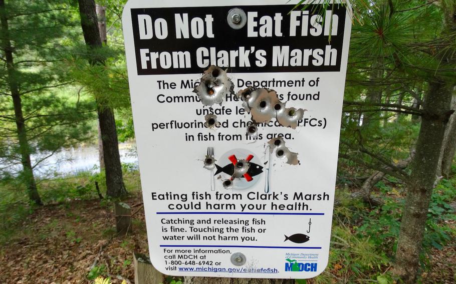 A sign at Clark's Marsh in Oscoda Township, Mich., warns of fish contaminated with PFAS/PFC chemicals leaching from the fire training area at the nearby former Wurtsmith Air Force Base grounds. Chemicals from fire fighting foam used on the base have created toxic plumes that are leaching through the local groundwater.