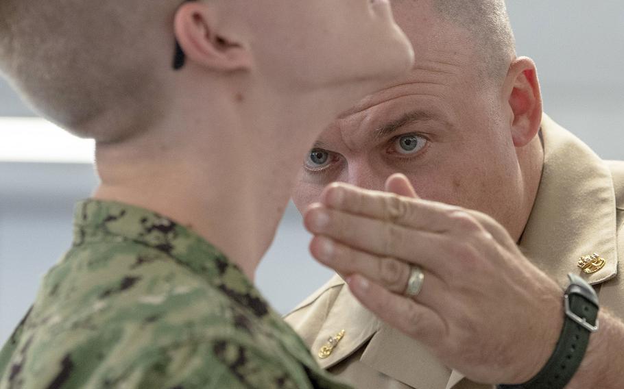 In an October, 2018 file photo, Chief Operations Specialist James Conyne, a recruit division commander, inspects the quality of a recruit's shave before a personnel inspection inside a compartment in the USS Kearsarge barracks at Recruit Training Command in Great Lakes, Ill.
