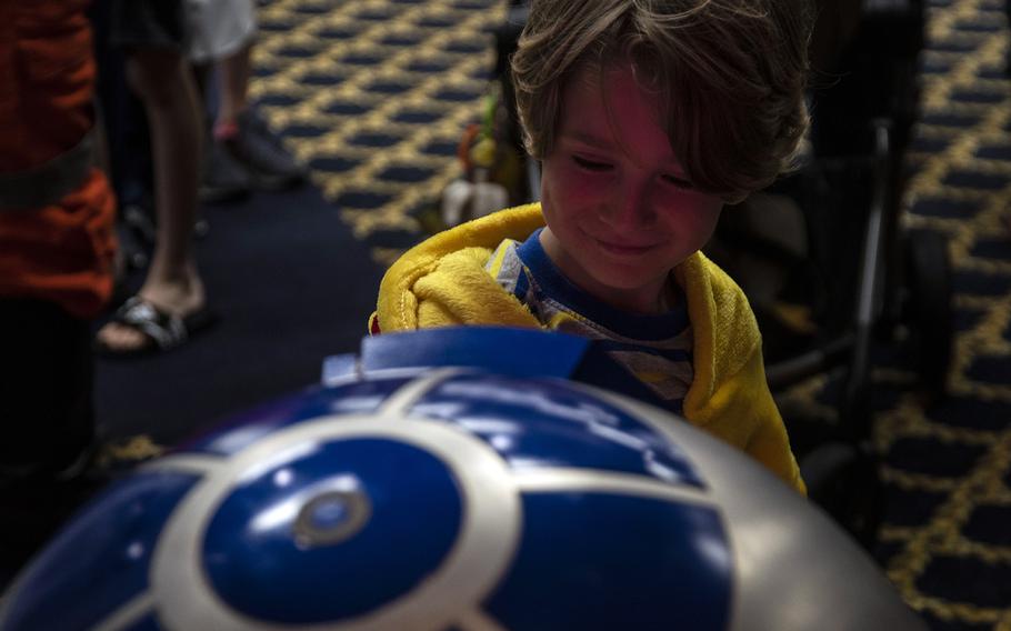 A child investigates a replica of R2-D2 from "Stars Wars" during the inaugural Yokota-Con at Yokota Air Base, Japan, Saturday, Oct. 19, 2019.  