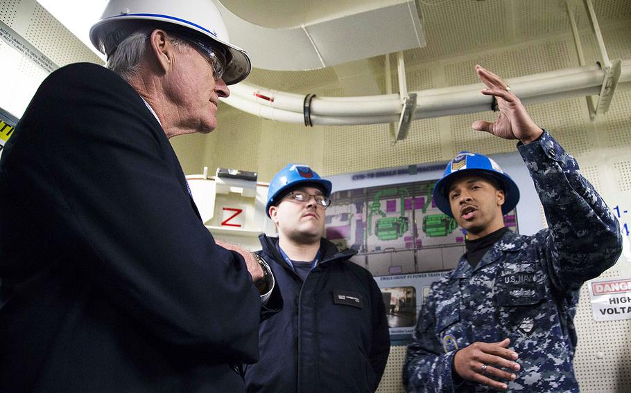 In a February 14, 2019 photo, Secretary of the Navy Richard V. Spencer, foreground, is briefed by Aviation Boatswain's Mate (Equipment) 1st Class Louis Mountain, assigned to USS USS Gerald R. Ford's air department, on Ford's electromagnetic aircraft launching system during a tour of the Navy's newest aircraft carrier.