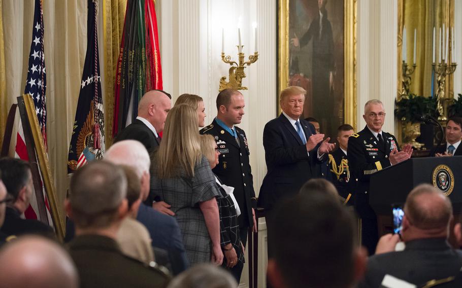 President Donald Trump joins in the applause for Army Master Sgt. Matthew Williams, who is standing beside the president with his family, during a Medal of Honor Ceremony in the East Room of the White House, Wednesday, Oct. 30, 2019, in Washington.