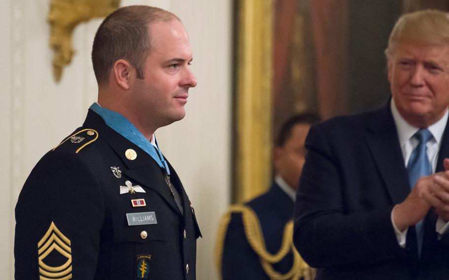 Master Sgt. Matthew Williams stands at attention after receiving the Medal of Honor as President Donald Trump joins in applauding Williams during a ceremony at the White House on Wednesday, Oct. 30, 2019.
