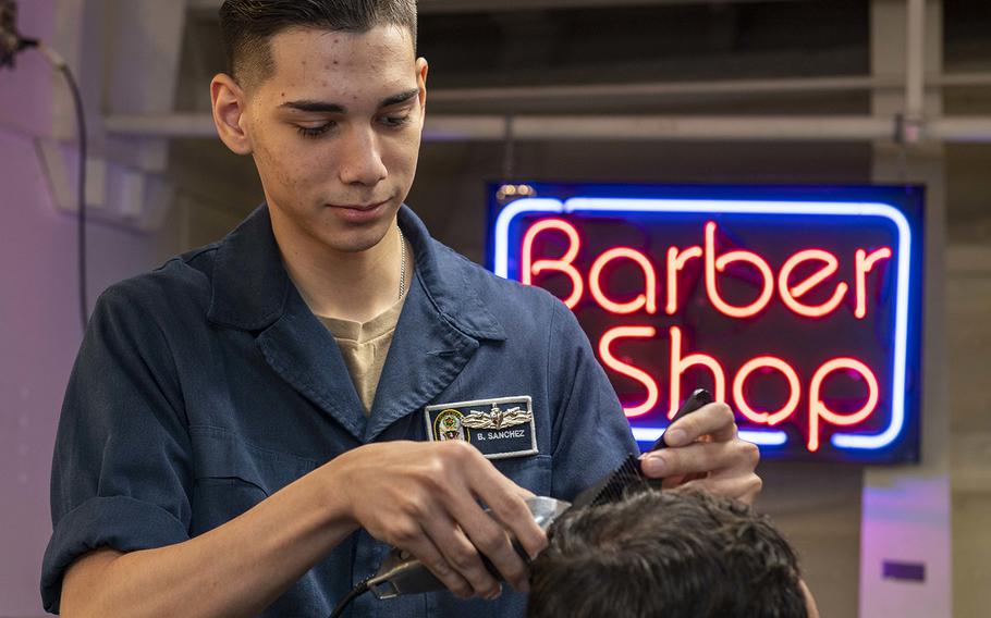 Seaman Brian Sanchez cuts a sailor’s hair aboard the amphibious assault ship USS Boxer. 