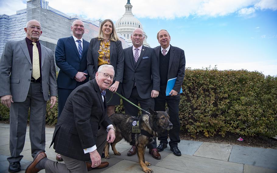 U.S. Rep. Ron Wright, R-Texas, kneels beside Axel, a retired law-enforcement dog, after Wright introduced the K-9 Hero Act in front of the Capitol in Washington on Thursday, Nov. 14, 2019. Standing behind from left are Bob Bryant with Mission K9 Rescue, Jason Johnson and Amanda Bolyard with Project K-9 Hero, Don Bramer with the Bramer Group, and Mark Stubis of American Humane.