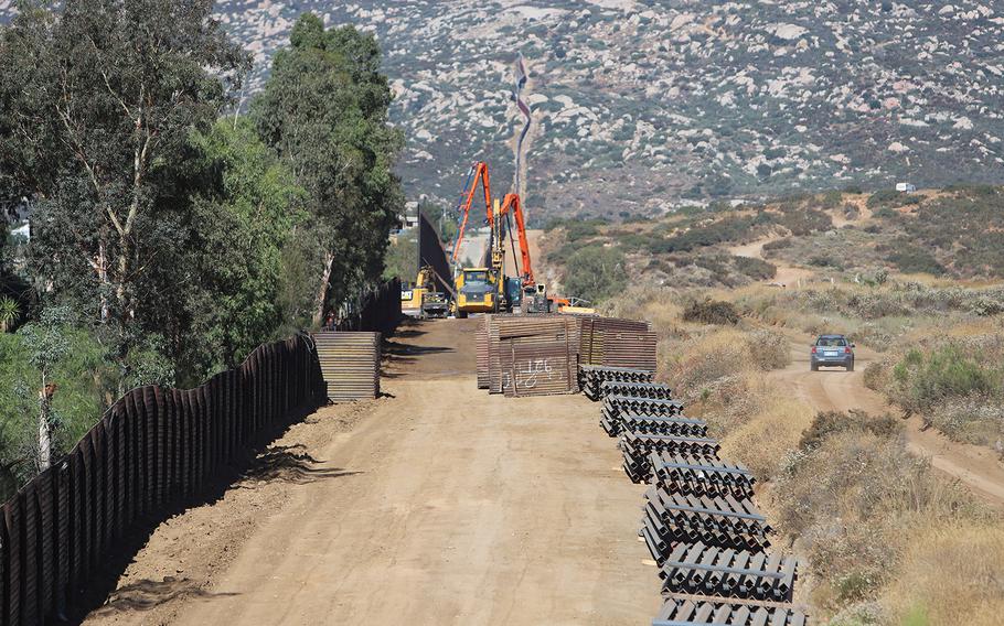 U.S. Army Corps of Engineers contractors place and align concrete-filled bollards at Tecate, CalifornIa on Aug. 9, 2019.