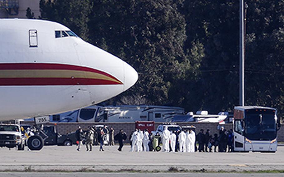Passengers board buses after arriving on an airplane carrying U.S. citizens being evacuated from Wuhan, China, at March Air Reserve Base in Riverside, Calif. Jan. 29, 2020.