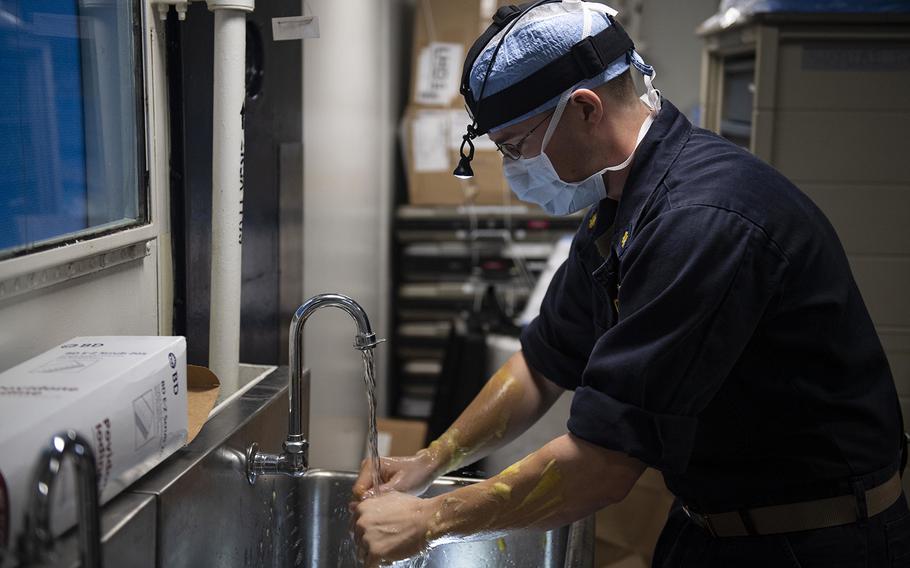 Lt. Cmdr. Justin Miller, a Navy surgeon washes his hands in preparation for surgery outside an operating room aboard the amphibious assault ship USS Wasp (LHD 1) while deployed in the Coral Sea on June 28, 2019.