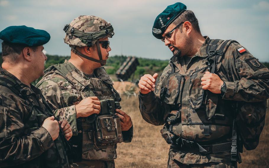 U.S. Army Chief Warrant Officer 2 Eric Land, center, assigned to 5th Battalion, 7th Air Defense Regiment, talks with Polish air defense artillery officers about the new MIM-104 Patriot surface-to-air missile system near Drawsko Pomorskiego, Poland, in June 2018. The Army is offering big bonuses to lure more warrant officers into the air defense artillery branch.

