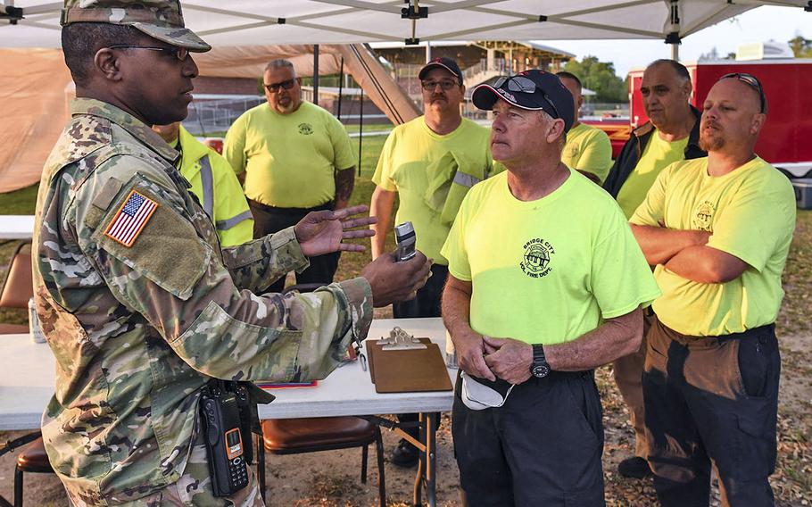 Lake Charles resident Capt. Julian Green, left, commander of the Louisiana National Guard's Headquarters and Headquarters Company, 2nd Battalion, 256th Infantry Brigade Combat Team, instructs Bridge City volunteer firefighters how to use a thermometer to vet medical personnel and first responders at a COVID-19 mobile testing center at the Alario Center in Westwego, La. March 21, 2020.