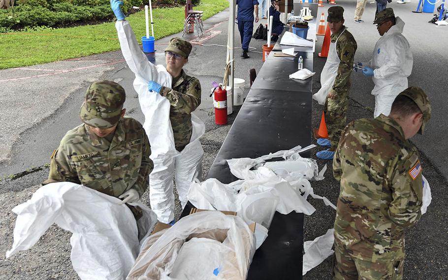 Louisiana National Guardsmen with the 256th Infantry Brigade Combat Team don protective suits to administer nasal swabs to first responders and medical personnel that exhibit COVID-19 symptoms at a mobile testing site at the Alario Center in Westwego, La., March 21, 2020.