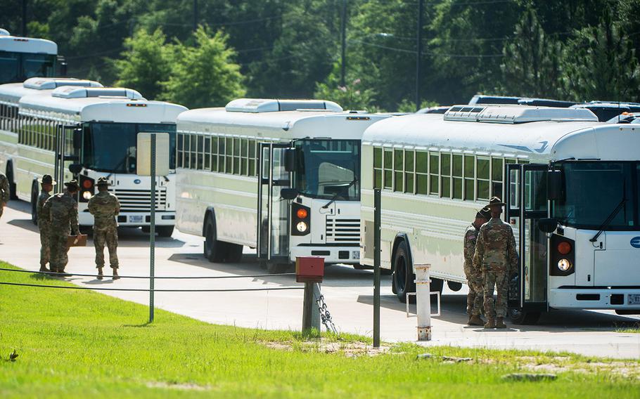 In a June, 2018 photo, drill sergeants at Fort Benning, Ga., stand by as busloads of new recruits pull in to start entry level training.